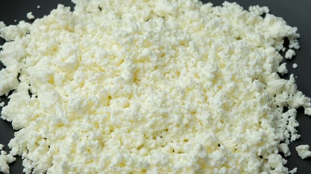 Organic crumbly curd cheese pile spinning close up video.