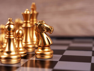 Golden chess knight in focus with other chess pieces in the background, illustrating strategic planning, leadership, competition, and tactical decision making. © Coompia77