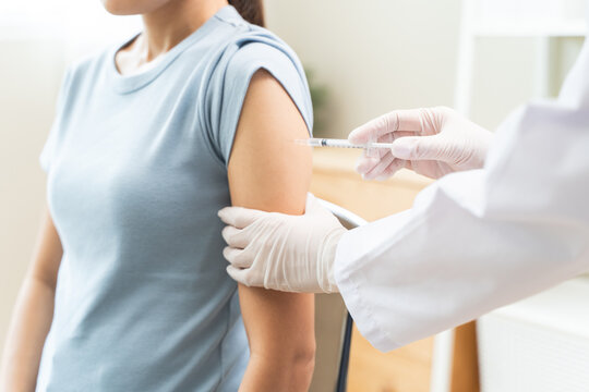 People getting a vaccination to prevent pandemic concept. Woman in medical face mask  receiving a dose of immunization coronavirus vaccine from a nurse at the medical center hospital