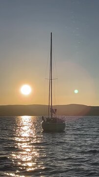 Old Sailboat Sails on the Wavy Sea on the Horizon During Sunset. Vertical video