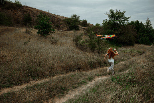 Small girl running with kite in big field