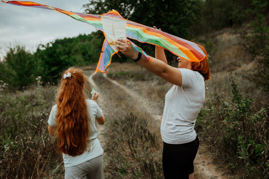 Mother and daughter catching rainbow kite in wind