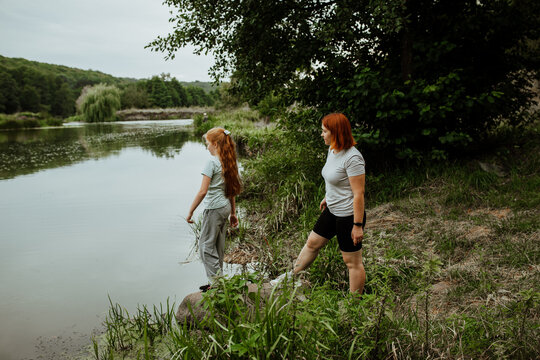 Mother and daughter standing on lake shore
