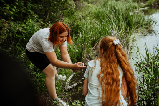 Mother and daughter by pond among green reeds