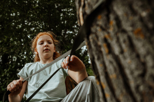 Girl tying hammock strap to tree trunk