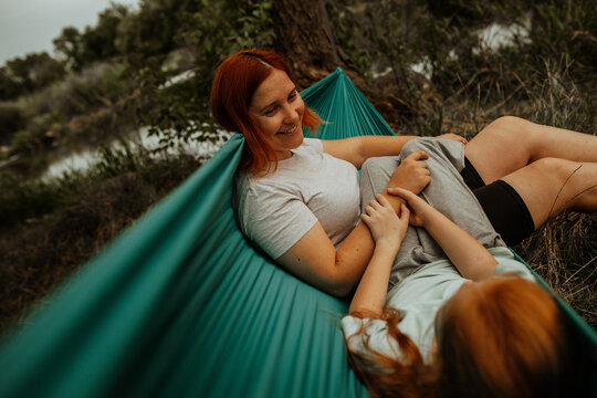 Mother lying in hammock laughing with daughter