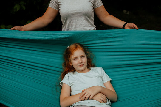 Mother swinging daughter in turquoise hammock