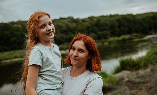 Smiling mother and daughter portrait by the lake