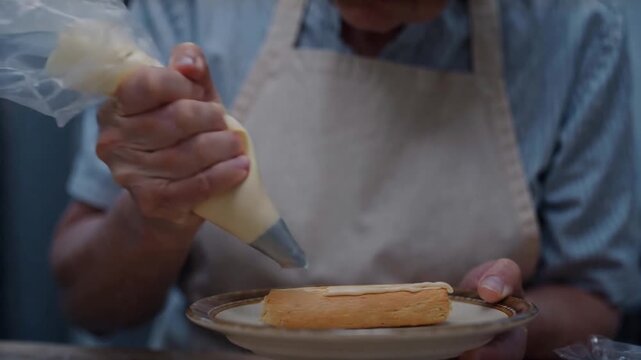 Pastry chef piping cream onto eclair