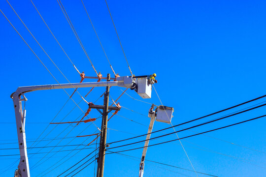Workers in bucket truck service overhead power lines on location is not identified.
