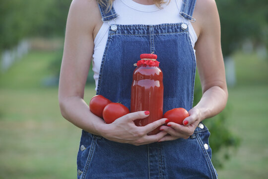 Woman holding homemade tomato juice in glass bottle, farm to table concept, organic food