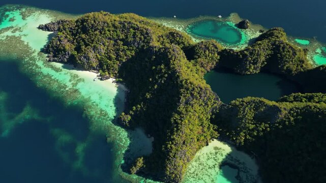 Aerial view of Coron Island with turquoise lagoons, limestone cliffs, and lush tropical vegetation surrounded by clear blue water in Coron, Mimaropa, Philippines.