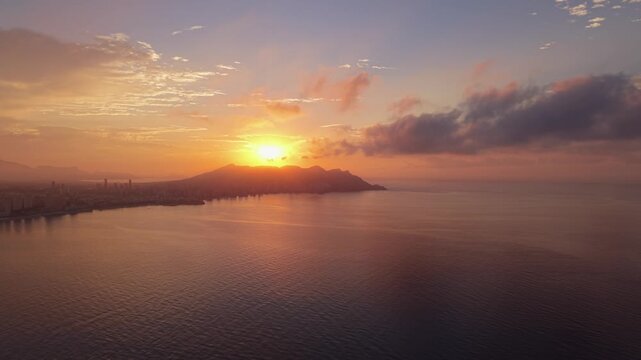 Aerial view of the Benidorm coastline at sunset with calm sea and distant mountains in Benidorm, Valencian Community, Spain.