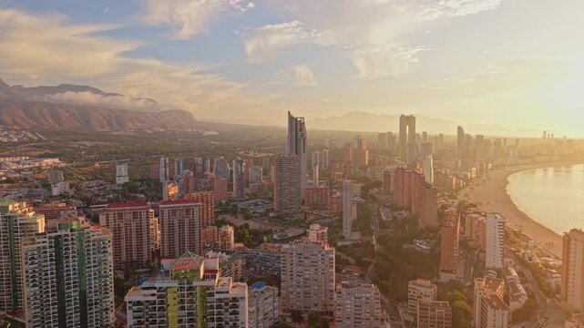Aerial view of the Benidorm skyline featuring tall skyscrapers along the sandy beach and Mediterranean coastline during golden hour in Benidorm, Valencian Community, Spain.