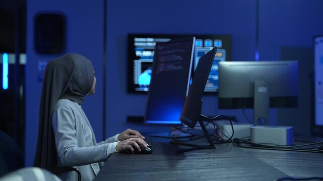 Muslim female developer wearing hijab coding on computer in modern office, Asian professional woman working on software development, Tech industry diversity and corporate programming business concepts