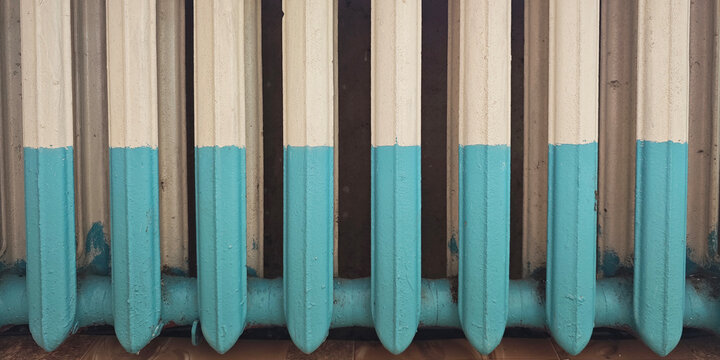 Cast iron radiator with turquoise and cream paint, worn industrial heating fixture with repeating vertical fins and a distressed surface