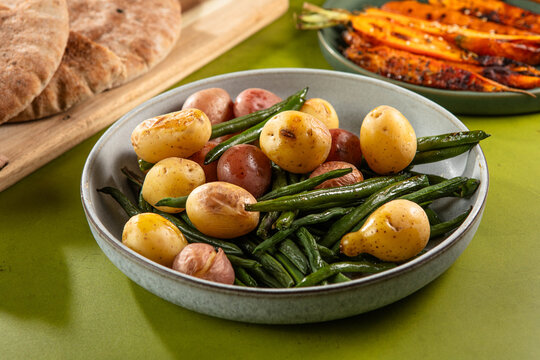 Fresh young potatoes and tender green beans served in a rustic table setting.