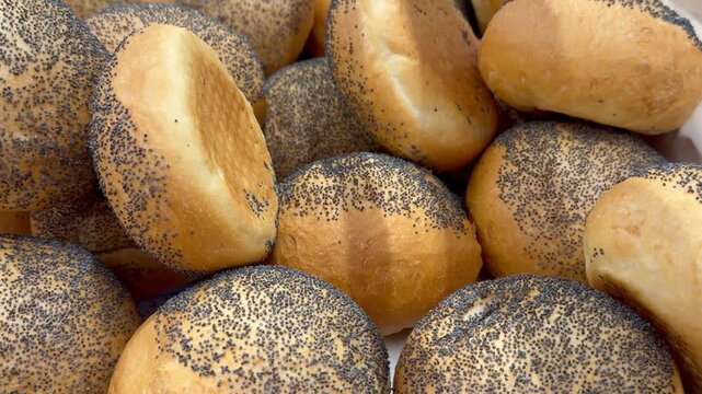 Crusty poppy seed bread rolls in bakery counter. Golden miniature buns form morning sandwich ingredient collection, baking tradition backdrop and sweet food market display.