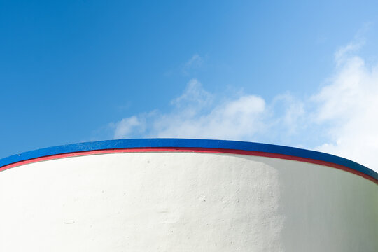 Curved White Wall with Red and Blue Trim Against a Blue Sky