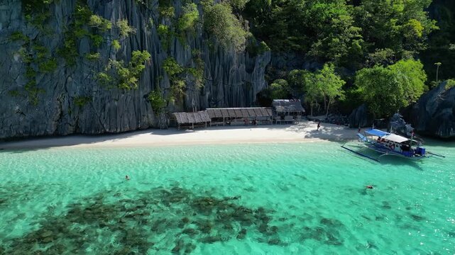 Aerial view of Coron Island beach with limestone cliffs, turquoise water, and a wooden hut in Coron, Mimaropa, Philippines.