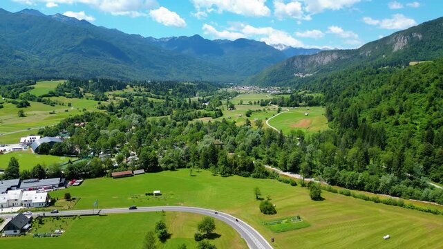 Lush Julian Alps valley in Slovenia, with a charming village, winding river, and majestic peaks under a bright summer sky. An idyllic scene for nature and travel. Bohinjska Bistrica