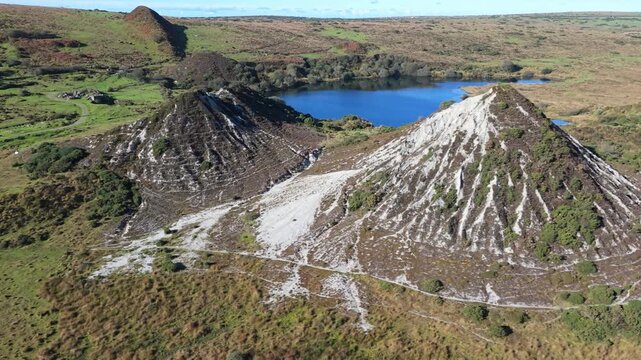 Aerial view of the disused china clay works and slag heaps in the Glynn Valley with a small lake in the background in Bodmin, Cornwall, United Kingdom.
