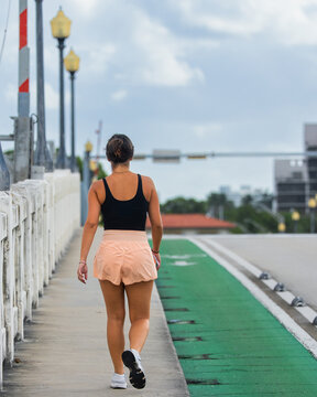 Woman Walking on a Bridge Sidewalk Beside a Green Bike Lane
