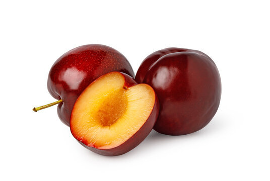 Ripe red plums with a halved plum showing golden flesh
