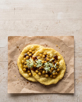 Trinidad doubles with bara flatbread, curried chickpeas, tamarind and cucumber chutney on paper, top view with copy space, vertical