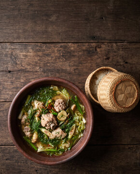 Thai northeastern kaeng om herbal curry with chicken and dill, with sticky rice, top view with copy space, vertical