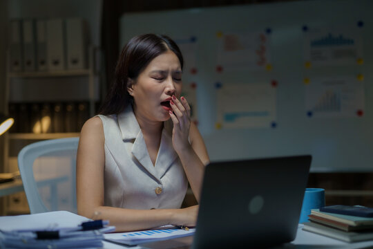 Tired businesswoman yawning working late in office
