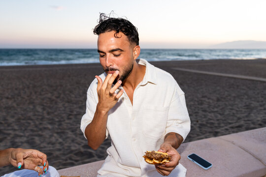 Man enjoying burger with ocean view at beach