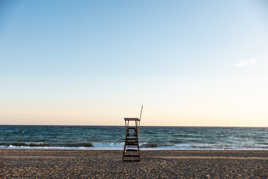 Lifeguard chair standing on empty beach at sunset