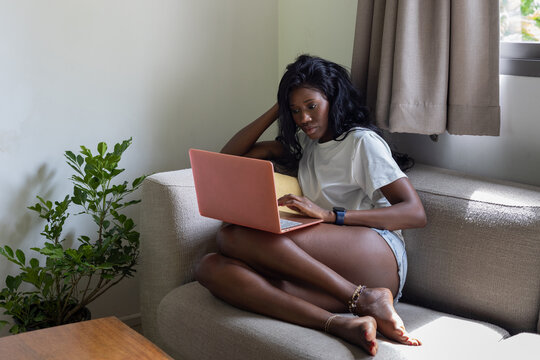 african american woman reads email on laptop computer at home