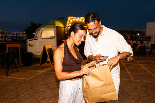 Young couple enjoying street food takeout at night