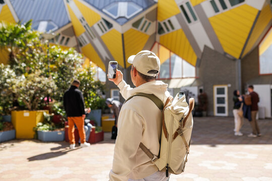 Man photographing Cube Houses with smartphone in Rotterdam