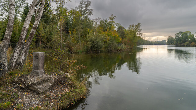 autumnal colored trees on vegetated lakeshore, lake with recreatonal place in Rhein valley, autumnal colored trees with orange and red leaves