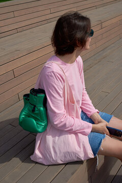 Woman sitting with boxing gloves hanging on pink tote bag