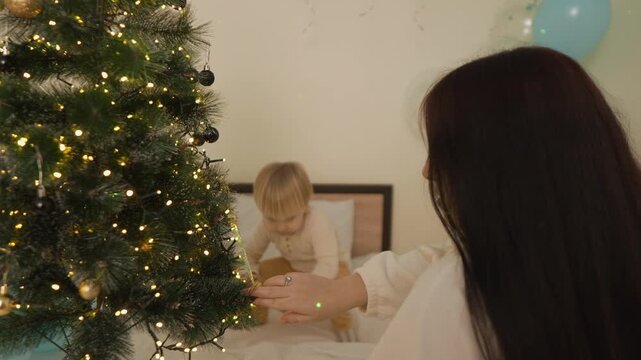 At Christmas, a toddler boy interacts closely with his smiling mother during holiday play. The close portrait view highlights positive parenting, togetherness and seasonal joy.