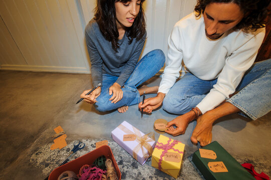 Couple preparing presents writing gift tags
