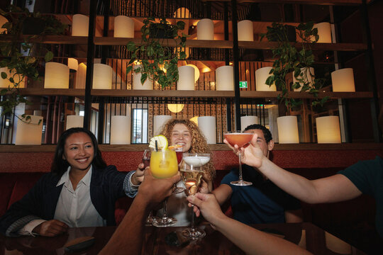 Group of diverse friends making a toast with cocktails
