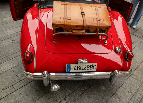 GANDIA, SPAIN - OCTOBER 4, 2026: Rear view of a red classic British sports car MGA 1500 1968 6 with a vintage leather suitcase mounted on the chrome trunk luggage rack.
