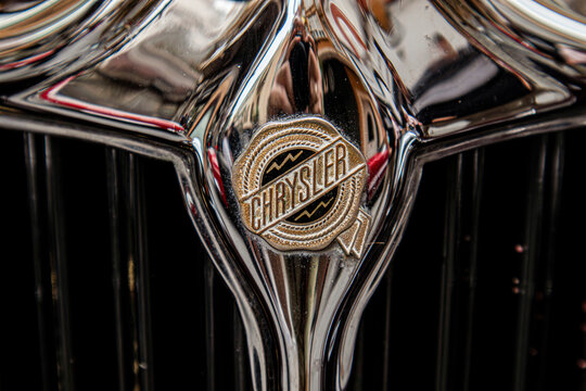 GANDIA, SPAIN - OCTOBER 4, 2026: Close-up of the vintage golden seal emblem and polished chrome radiator grille on a classic Chrysler motor vehicle.
