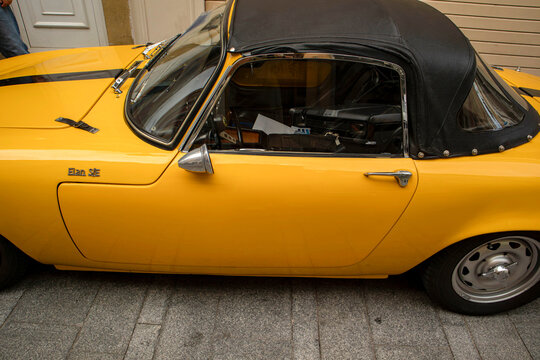 GANDIA, SPAIN - OCTOBER 4, 2026: Side profile view of a vintage yellow 1967 Lotus Elan S3 SE DHC sports car featuring a black convertible soft top.