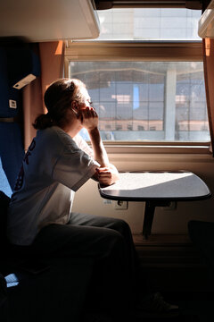 Woman looking out train window in compartment