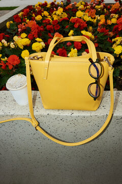 Yellow bag and coffee cup against colorful flowers. Flash