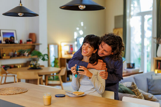 Couple embracing happily in pajamas enjoying morning breakfast at home