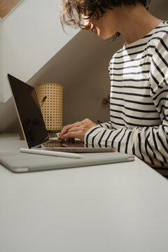 Female freelancer sitting at home office desk working on laptop.