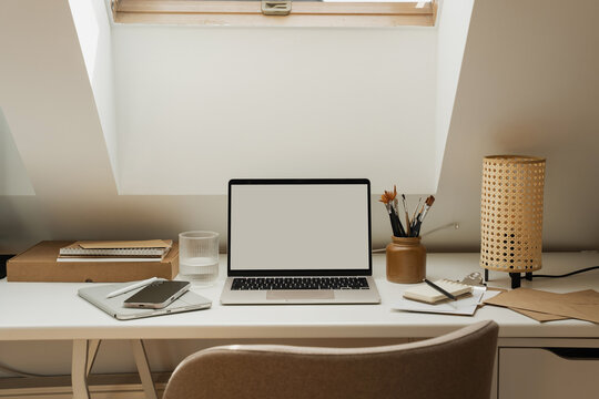 Laptop computer mockup on desk below open roof skylight window