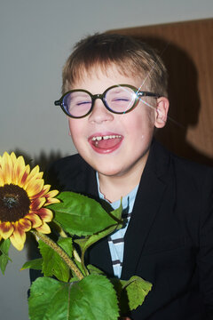 Smiling boy with glasses holding sunflower